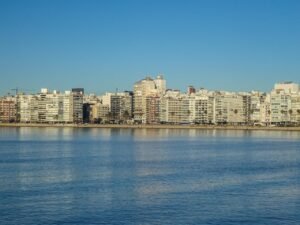 Skyline da orla de Pocitos em Montevideo, Uruguai, visto das águas do Rio da Prata. A imagem mostra a linha de edifícios residenciais modernos ao longo da Rambla, sob um céu azul limpo e águas calmas em primeiro plano.