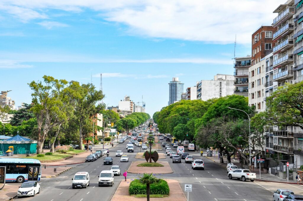 avenida dupla com diversos veículos em circulação com prédios e o céu azul ao fundo avenida 18 de Julio no Uruguai