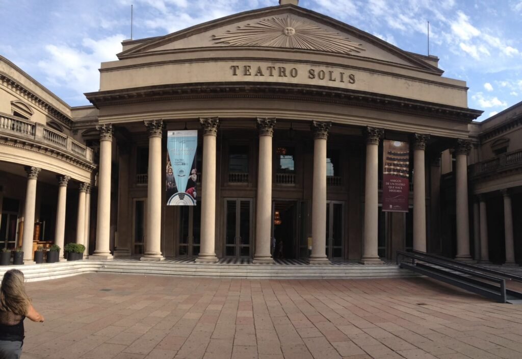 Fachada frontal do Teatro Solís com colunas altas, escadarias e estandartes em uma praça ensolarada melhores hotéis em Montevideo