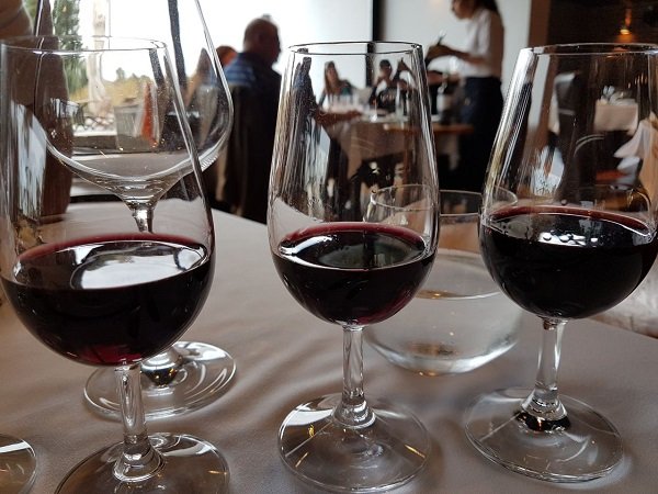 taças com vinhos em mesa de restaurante e pessoas ao fundo quanto custa uma viagem para o Uruguai