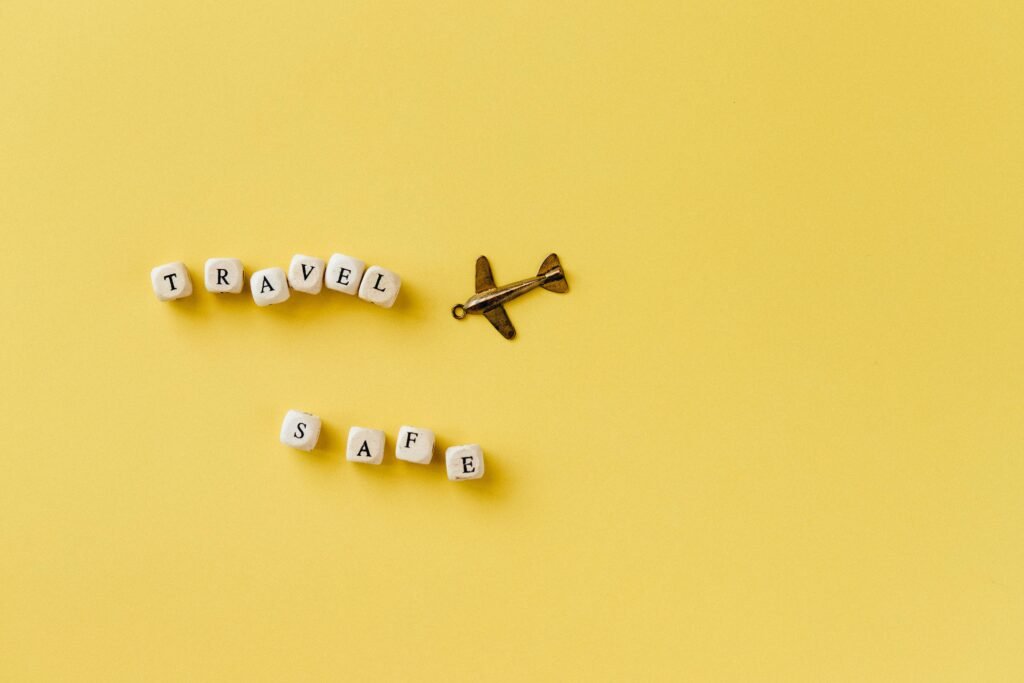 Vintage toy airplane beside letter blocks spelling 'TRAVEL SAFE' on a yellow background.