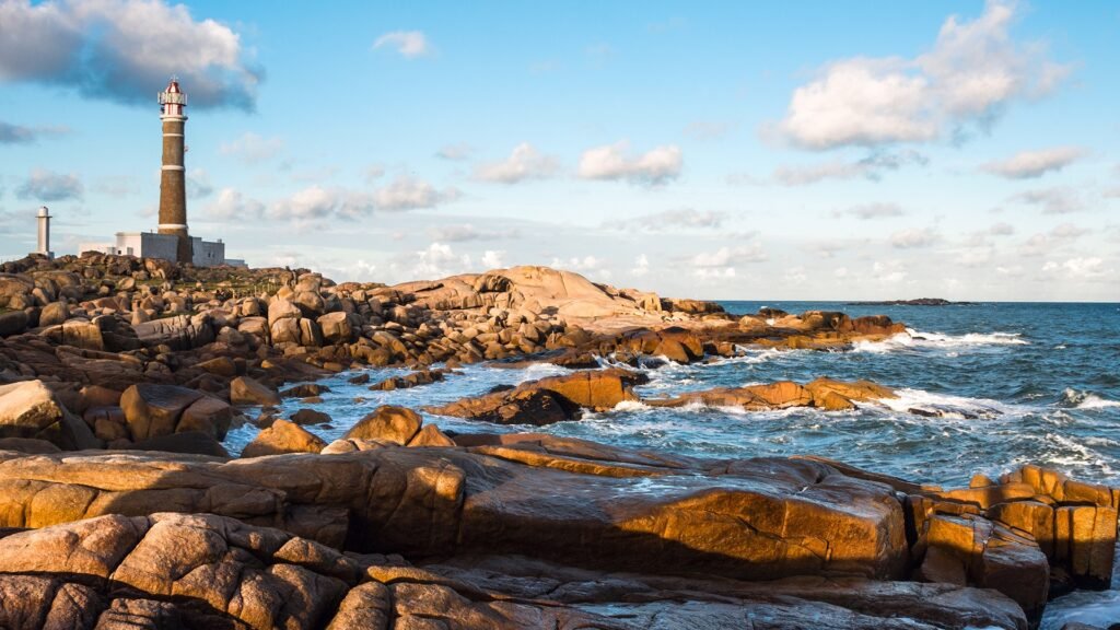 região de praia com rochas, mar e o céu azul ao fundo