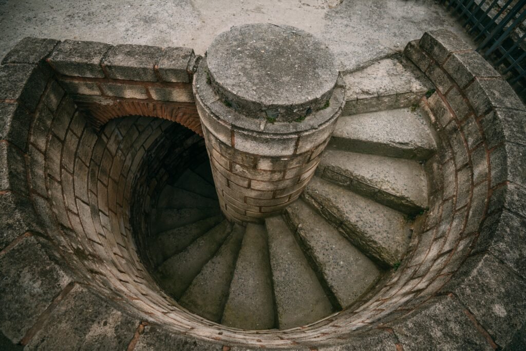 Vista de cima para baixo de uma escada em espiral de pedra desgastada, que desce em torno de uma coluna central em um poço de tijolos Farol de Punta Carretas em Montevideo