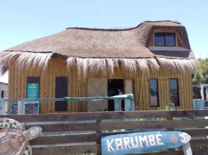 Construção de madeira com telhado de palha e letreiro Karumbé na entrada