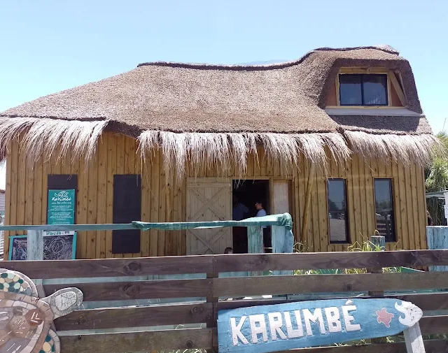 Construção de madeira com telhado de palha e letreiro Karumbé na entrada