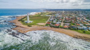 Vista aérea de La Paloma com o farol branco, a costa rochosa e as casas do balneário