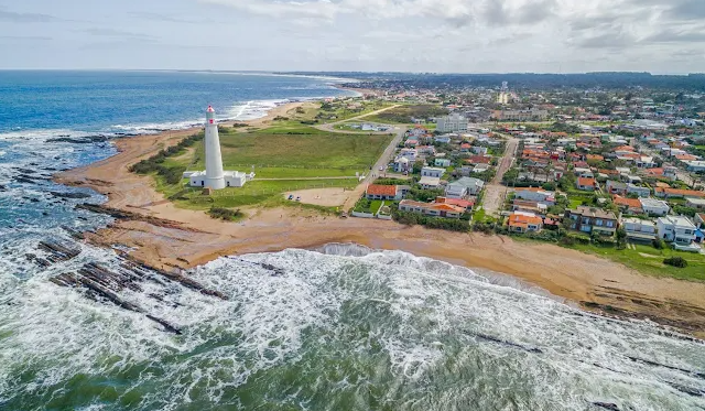 Vista aérea de La Paloma com o farol branco, a costa rochosa e as casas do balneário