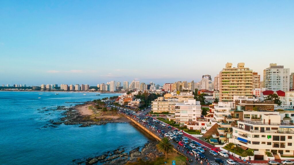 O horizonte de uma cidade costeira, com modernos arranha-céus ao longo da orla e uma movimentada avenida paralela à costa