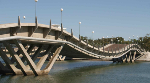 Ponte ondulada Leonel Viera sobre a Laguna Garzón, com pilares de concreto inclinados em formato de V e postes de iluminação esféricos, em Punta del Este, Uruguai.
