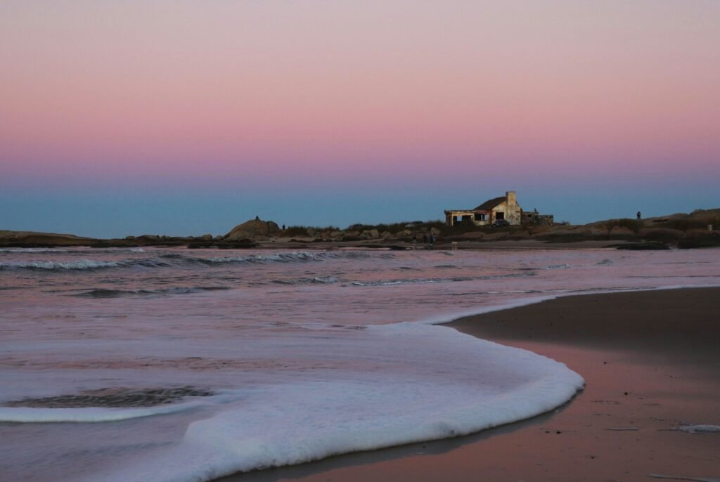 mar, areia, céu colorido ao fundo