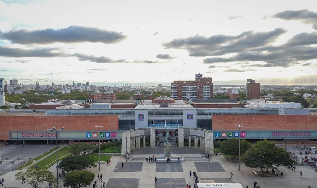 Fachada do shopping e terminal Tres Cruces com letreiro Bienvenidos e praça em frente