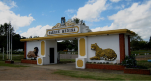 `Entrada do Zoo Parque Medina com murais de leão e onça-pintada na fachada branca`