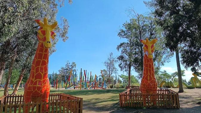 Esculturas de girafas coloridas e playground infantil no Parque El Jaguel