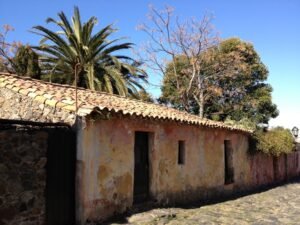 Barrio histórico de Colonia del Sacramento: casario colonial português com paredes de pedra e telhado de telhas de barro ao lado de rua de paralelepípedos