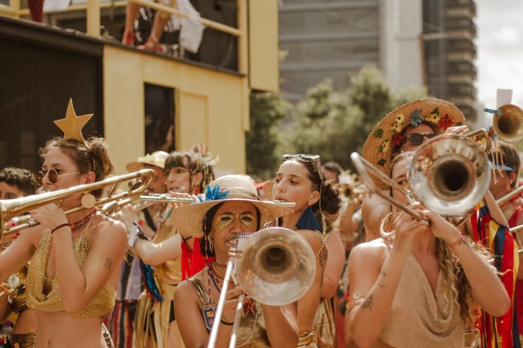 Bloco de carnaval com músicos de chapéu e instrumentos de sopro em desfile em La Pedrera