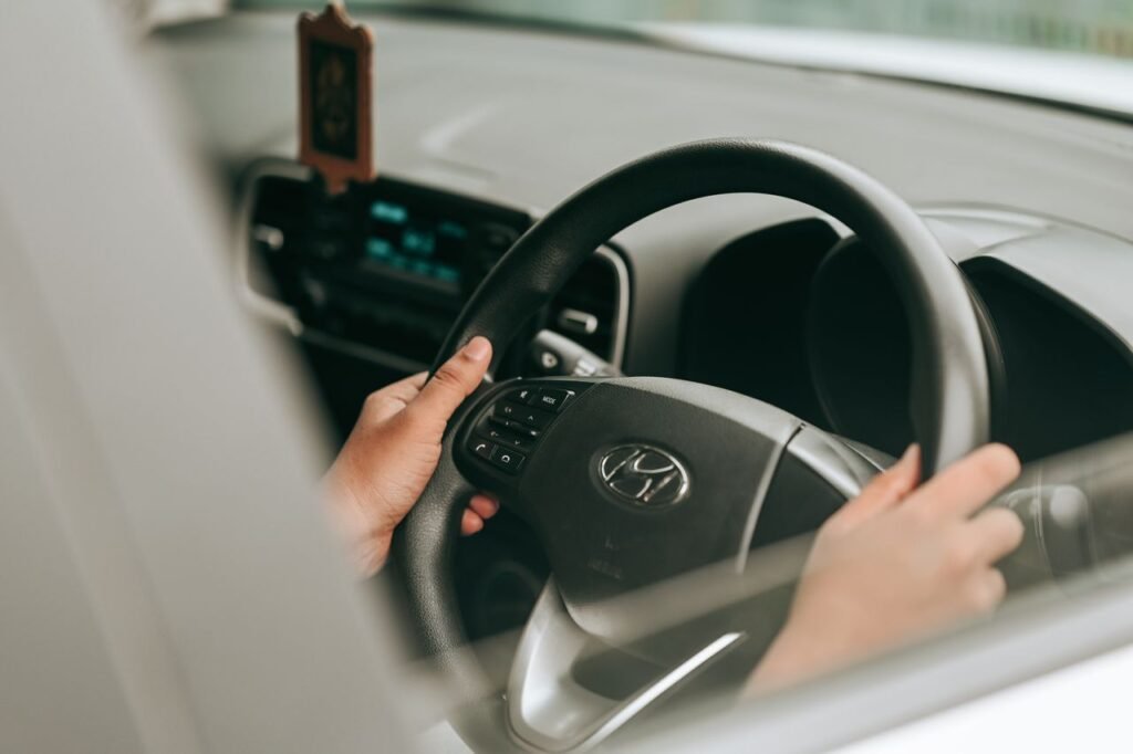 mãos de uma pessoa segurando o volante de um carro da marca Hyundai.