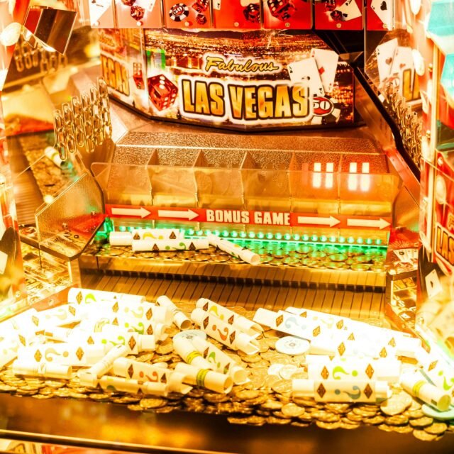 Interior de máquina caça-níqueis com tema de Las Vegas, com moedas brilhantes, rolos de papel coloridos e uma placa proeminente de 'JOGO BÔNUS' na parte inferior casino no Montevideo Shopping
