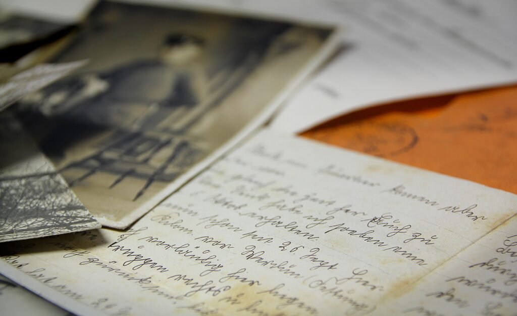 Close-up de letras cursivas manuscritas espalhadas sobre uma mesa, com uma foto desfocada em preto e branco e um envelope laranja por perto correios no Uruguai