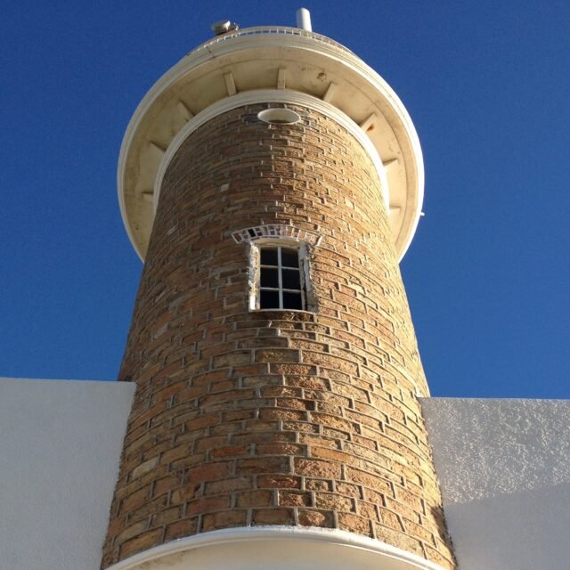 Farol de tijolos da Praia de Punta Carretas visto de baixo contra o céu azul