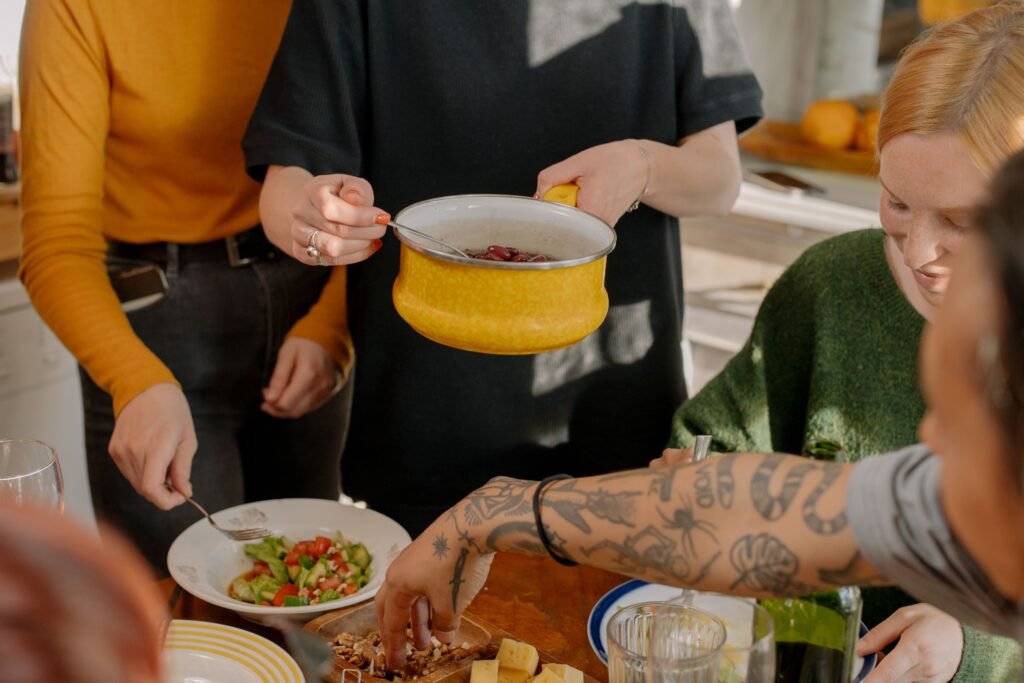 As pessoas se reuniam em volta de uma mesa para compartilhar a refeição, sendo servida uma panela amarela com feijão ou sopa.