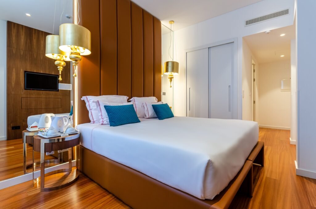 quarto de hotel com cama, espelho, lampadas e demais acessórios e móveis