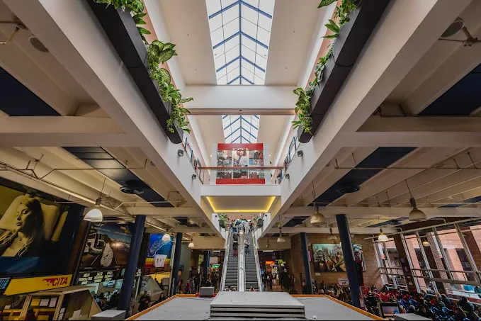 Interior do shopping Tres Cruces com escadas rolantes e claraboia no teto