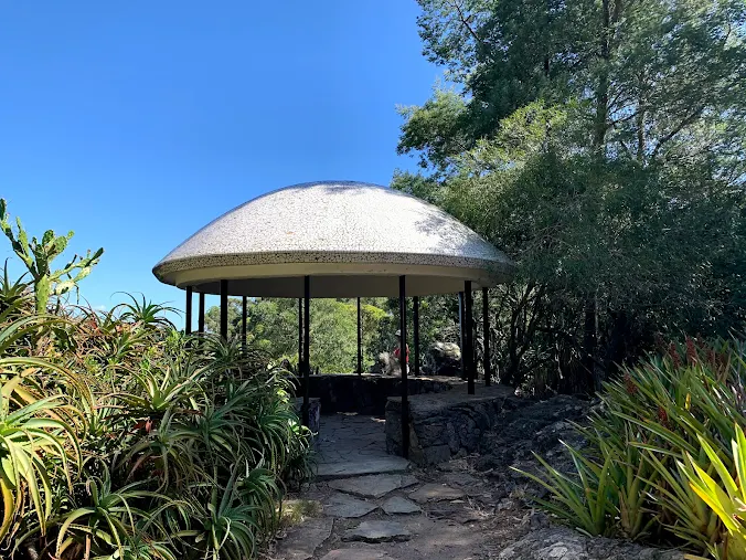 Mirante com cúpula de pedra cercado de vegetação no Arboretum Lussich