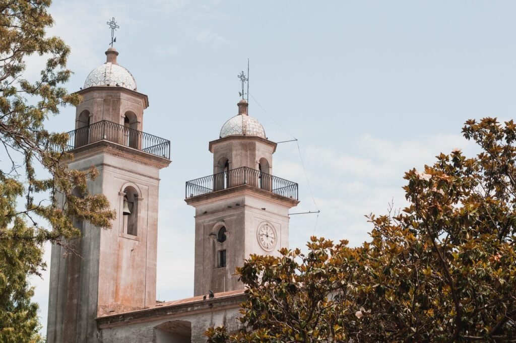 As duas torres da Basílica do Santíssimo Sacramento, com cúpulas e cruzes, vistas entre as árvores no barrio histórico de Colonia del Sacramento
