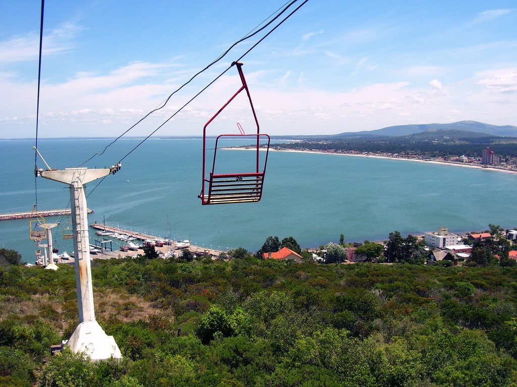 Cadeirinha vermelha do teleférico (aerosilla) do Cerro San Antonio com vista para a baía, o porto e a orla de Piriápolis, no Uruguai.