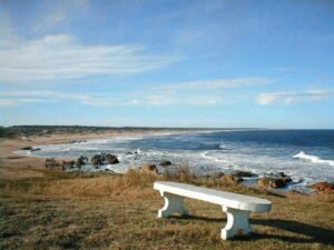 Banco branco em mirante com vista para a costa rochosa das praias de La Pedrera