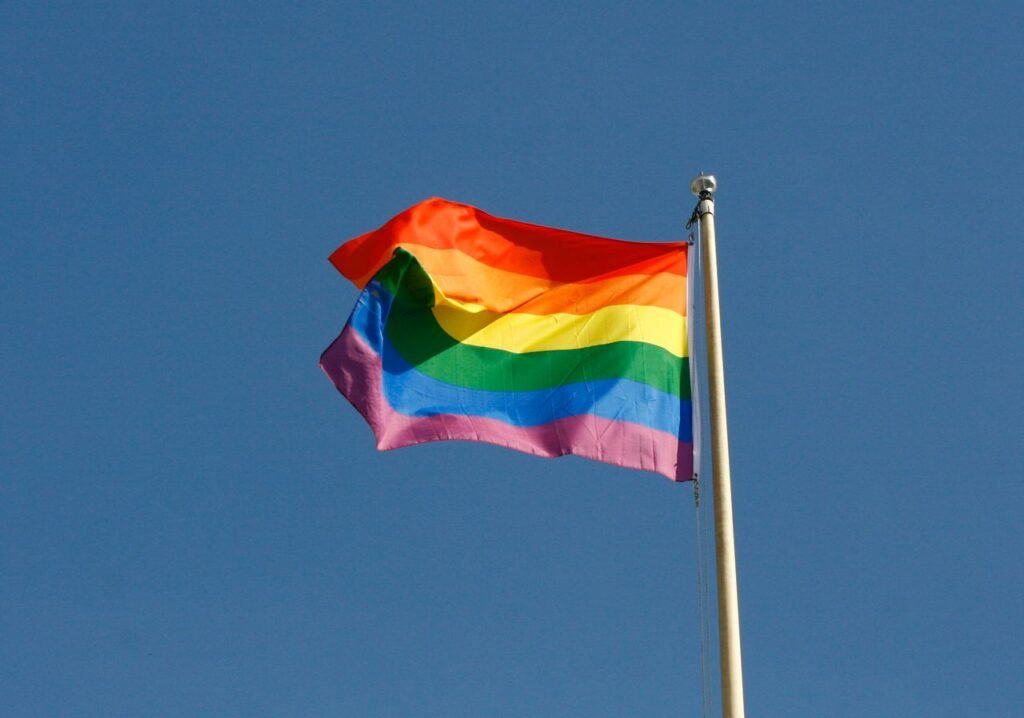Bandeira do arco-íris LGBTQIA+ tremulando no mastro contra o céu azul, símbolo do Uruguai gay friendly