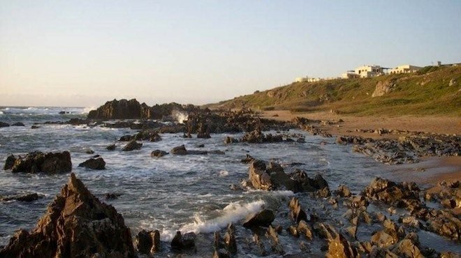 Costão rochoso de La Pedrera com casas no alto da encosta ao entardecer