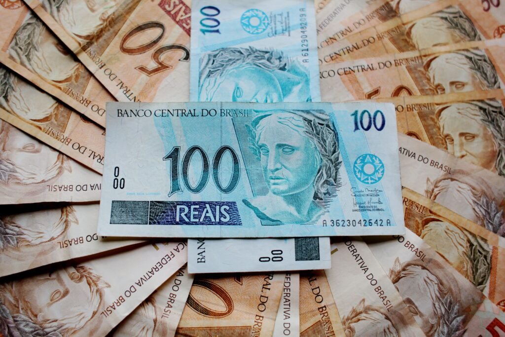 Nota azul de 100 reais centralizada entre várias notas de reais brasileiros; nela, é possível ler a inscrição "BANCO CENTRAL DO BRASIL".