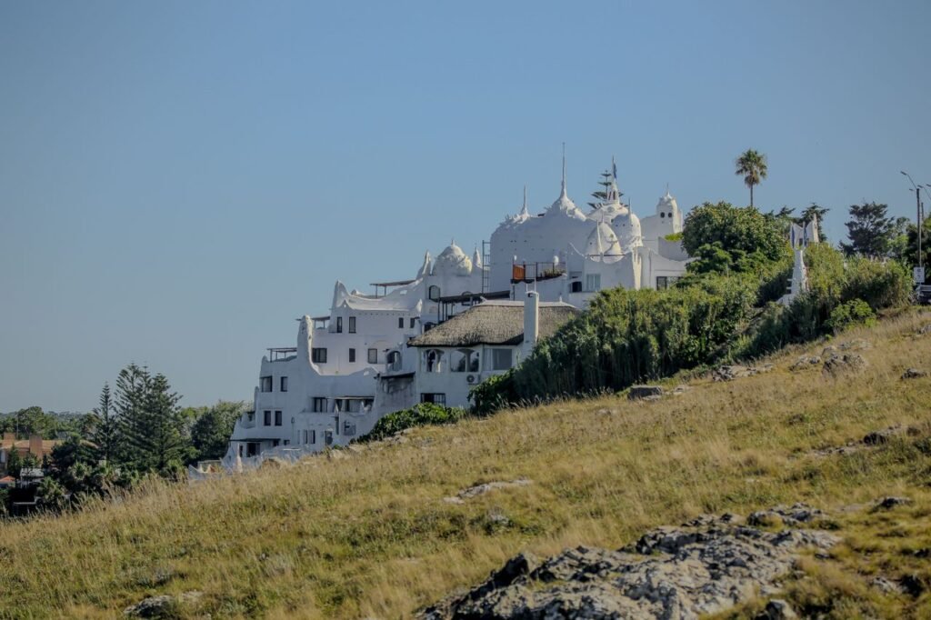 Casapueblo visto da encosta, com sua arquitetura branca escultórica dominando o morro de Punta Ballena