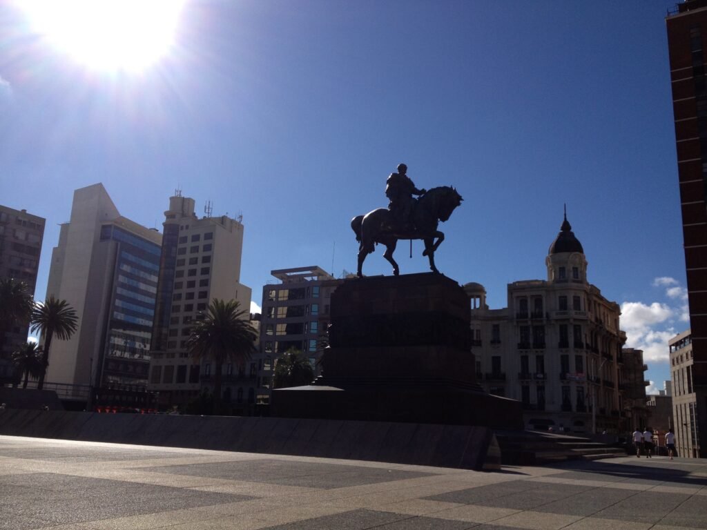 imagem de estátua em praça com o céu azul ao fundo