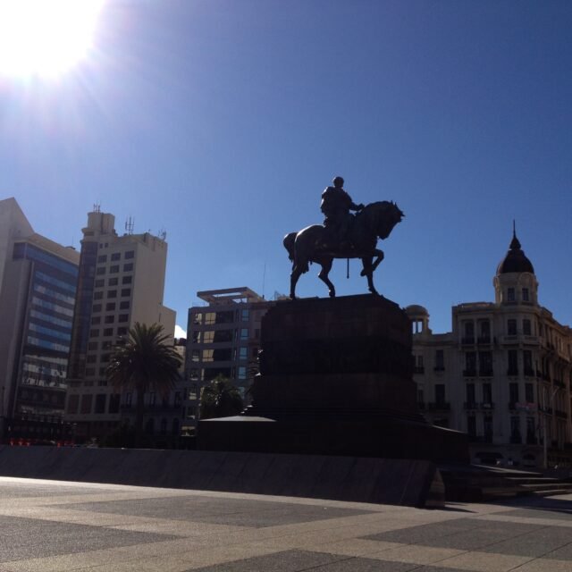 imagem de estátua em praça com o céu azul ao fundo