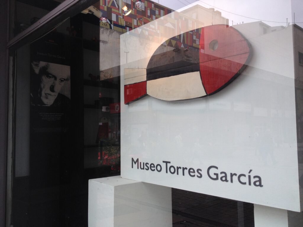 Vitrine do Museo Torres García, com uma grande escultura circular abstrata em vermelho e branco refletida no vidro.