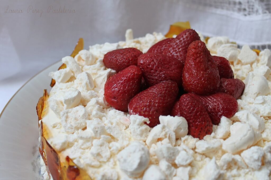 Close-up de um bolo coberto com morangos vermelhos frescos e pedaços de suspiro branco esfarelados.