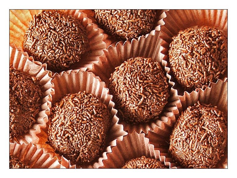 Trufas de chocolate cobertas com granulado, em forminhas de papel e dispostas em uma bandeja.