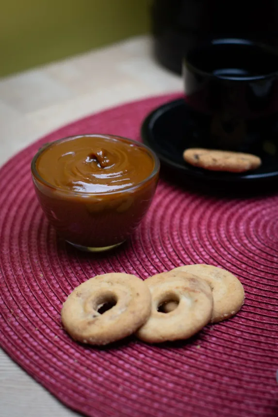 Doce de leite em uma tigela ao lado de biscoitos sobre a mesa