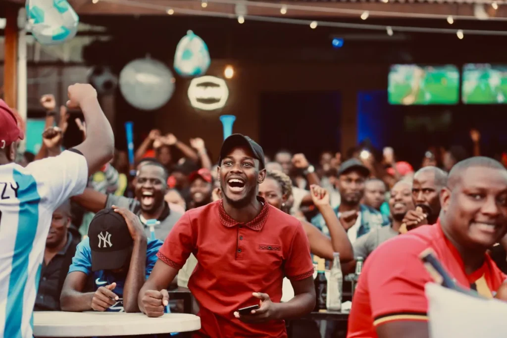 Torcedores comemorando dentro de um bar com teloes exibindo futebol