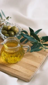 Jarra de vidro com azeite de oliva ao lado de azeitonas e ramos