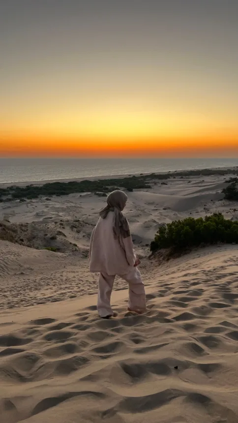 Pessoa observando o campo de dunas ao pôr do sol