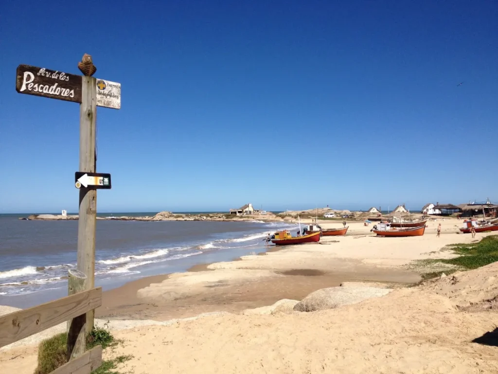 Placa de madeira na areia indicando os caminhos de Cabo Polonio