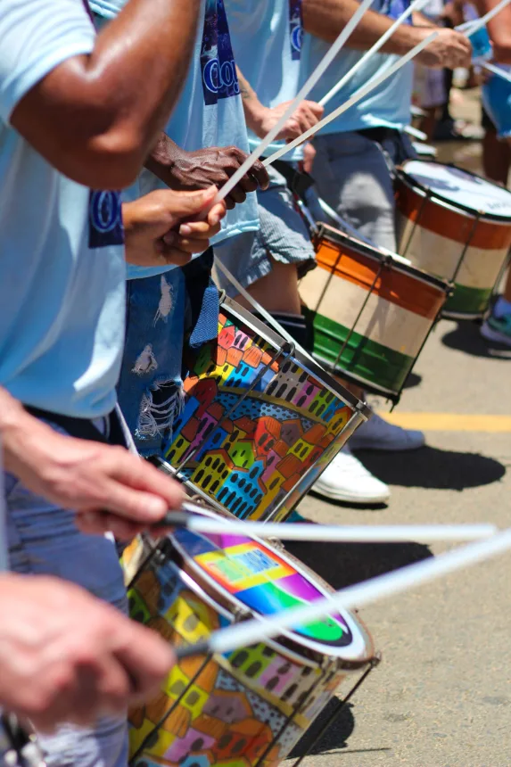 Mãos tocando tambores pintados durante o desfile na rua