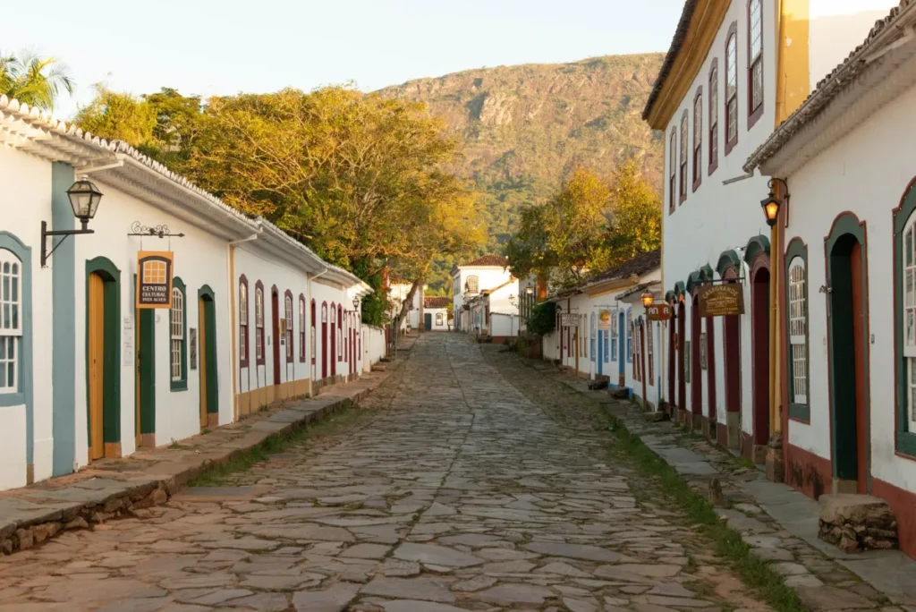 Rua de pedra com casario colonial branco em cidade pequena