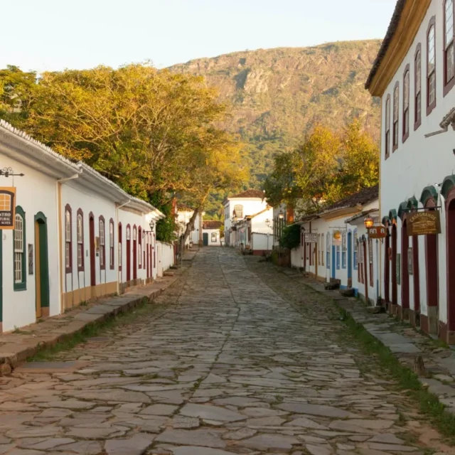 Rua de pedra com casario colonial branco em cidade pequena