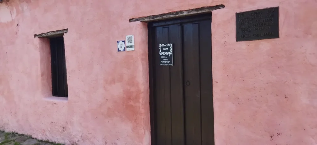 Fachada rosa da Casa Nacarello com porta de madeira e placa histórica
