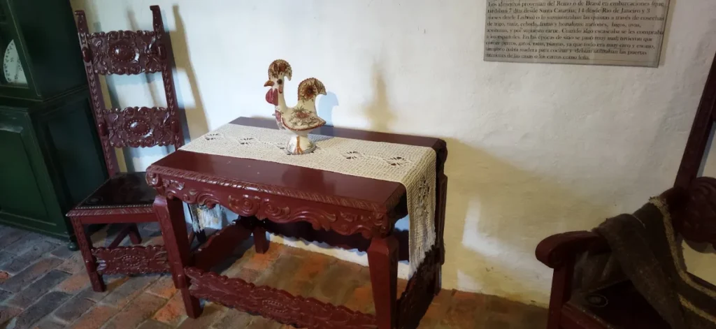Mesa e cadeiras de madeira entalhada com toalha de renda no interior da casa