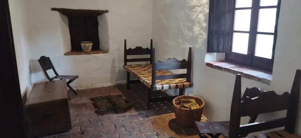 Sala caiada com nicho na parede, cadeiras antigas e janela de madeira